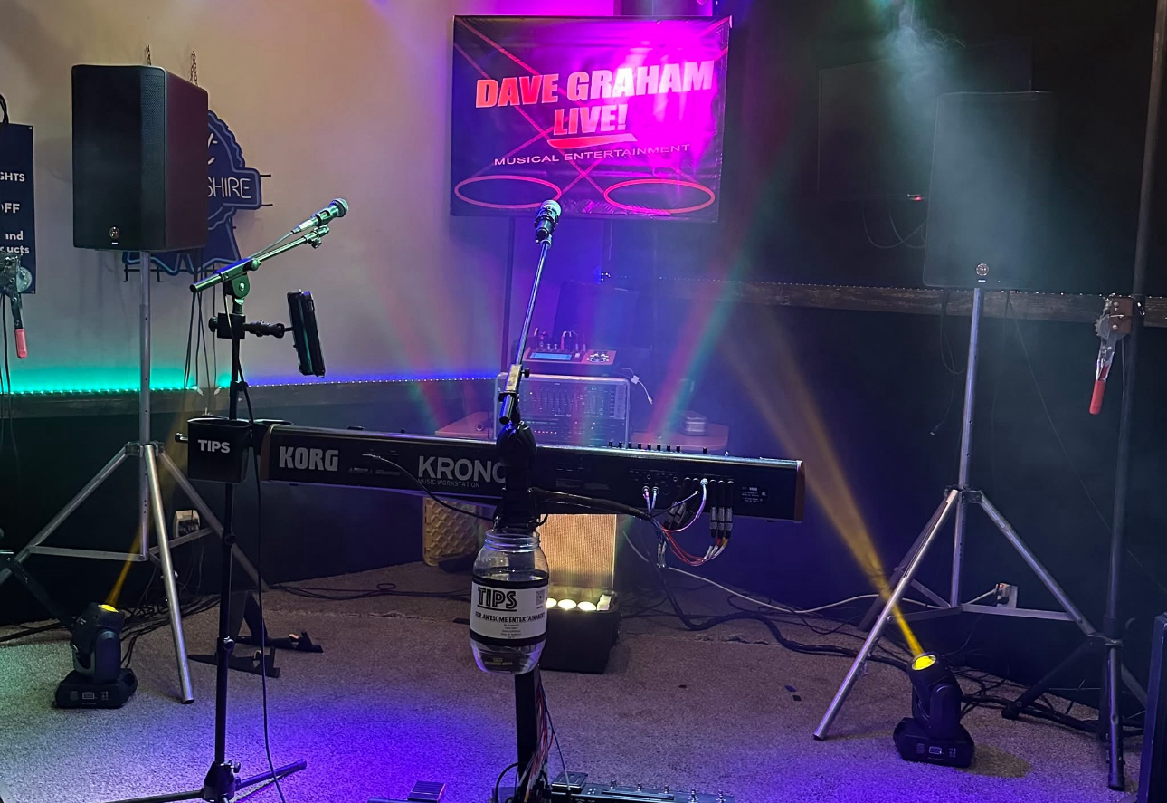 Dave performing live at his keyboard with stage lighting and sound equipment